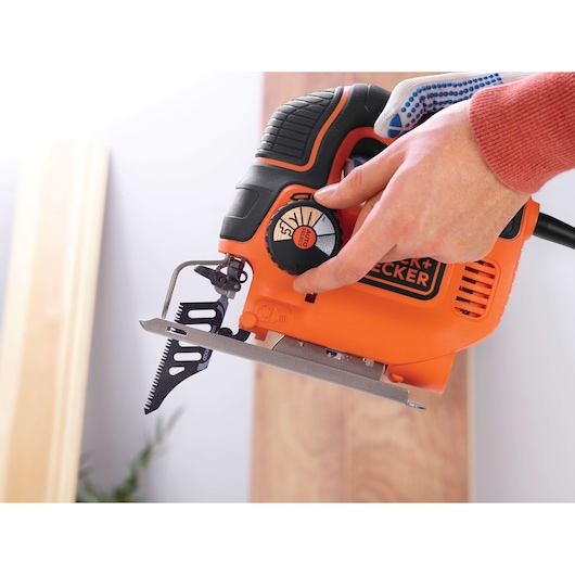 BLACKDECKER KS901SEK orange jigsaw tool in use, close-up photography of adjustment dial and blade.