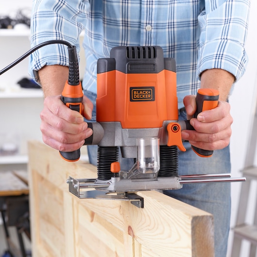 Photo of BLACK+DECKER KW1200E woodworking router used on a wooden board, close-up view.