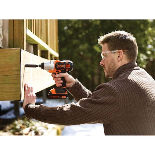 BLACKDECKER MT218K cordless drill being used outdoors on wood, visible lithium battery, product in hand.