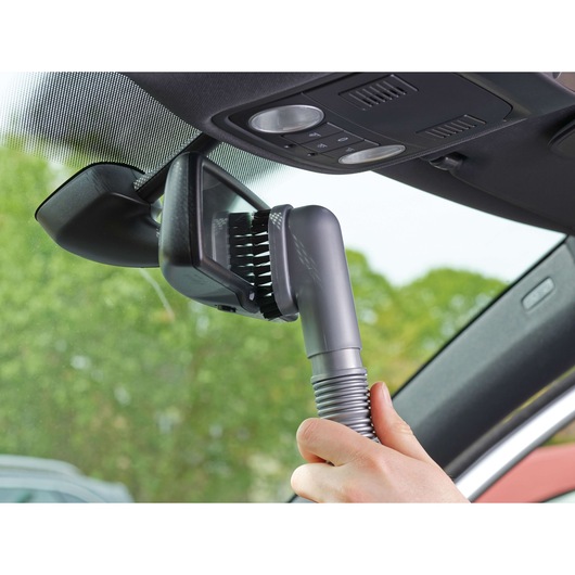 BLACKDECKER NV1210AV handheld vacuum cleaning car interior near mirror with brush attachment.