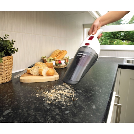 BLACK+DECKER NV3610N handheld vacuum cleaning bread crumbs from kitchen countertop, bread in background.