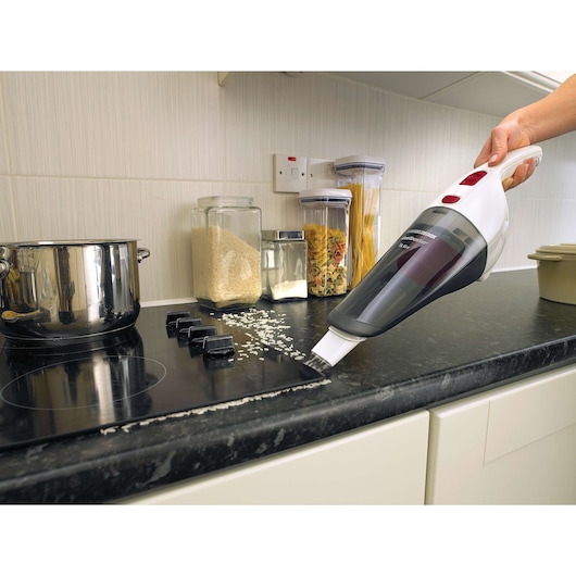 BLACKDECKER NV3620N handheld vacuum cleaning rice on kitchen counter, side angle.