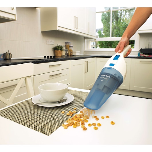 BLACKDECKER NW3620N handheld vacuum cleaning spilled cereal on kitchen table, side angle.