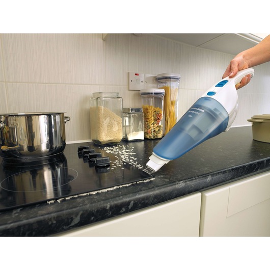 BLACKDECKER NW3620N handheld vacuum cleaning rice from kitchen counter, side angle.