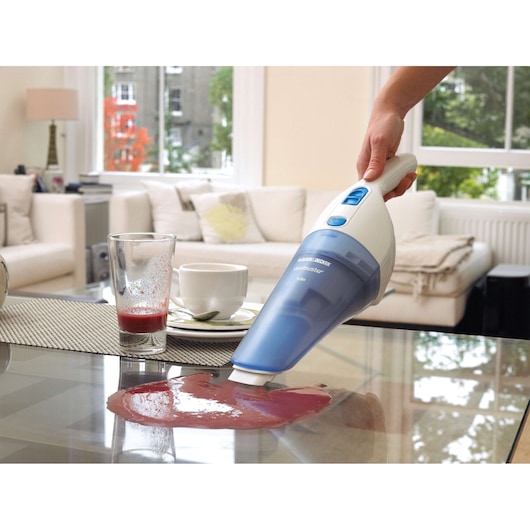 BLACKDECKER NW3620N handheld vacuum cleaning spilled juice on coffee table in modern living room.