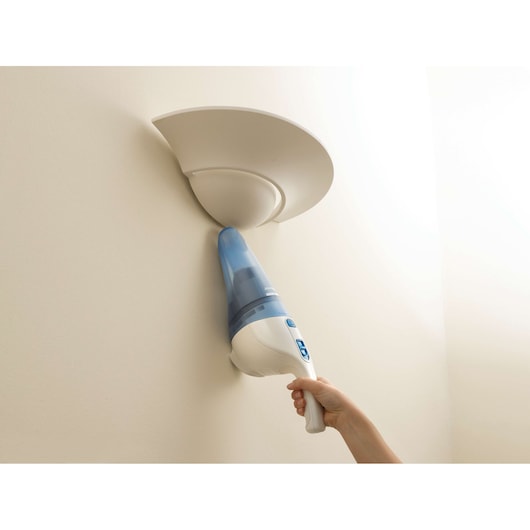 BLACKDECKER NW3620N handheld vacuum cleaning near a wall-mounted light fixture.
