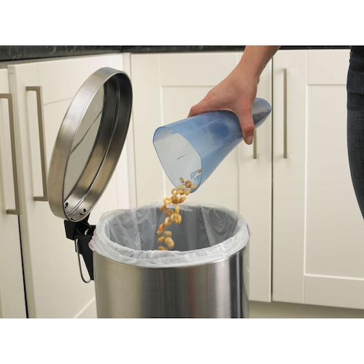 BLACKDECKER NW3620N handheld vacuum dust container being emptied into a stainless steel trash can in a kitchen.