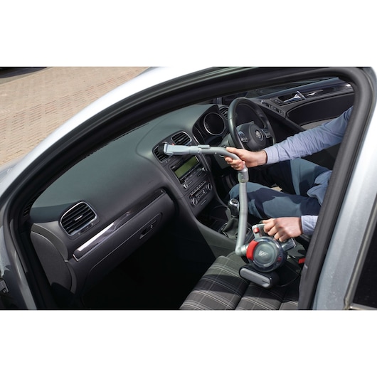 BLACKDECKER PD1200AV handheld car vacuum cleaner used inside vehicle, flexible hose visible.