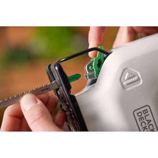 Close-up photo of a BLACK+DECKER REVJ12C jigsaw, with a hand inserting a saw blade into the tool.
