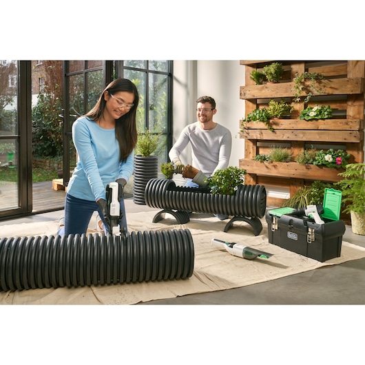 BLACKDECKER REVHD12C cordless drill used in indoor gardening with black storage box and green lid.