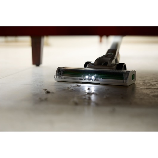 BLACKDECKER REVSV18D1 vacuum with LED lights cleaning under furniture, low-angle view, collecting dust and debris.