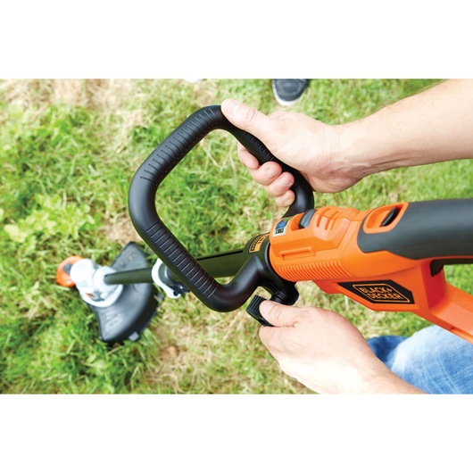 Photo of BLACKDECKER STC1840 grass trimmer handled by person on lawn.